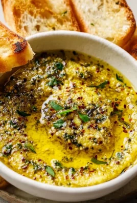Delicious garlic olive oil dip served in a bowl with herbs and bread for dipping.