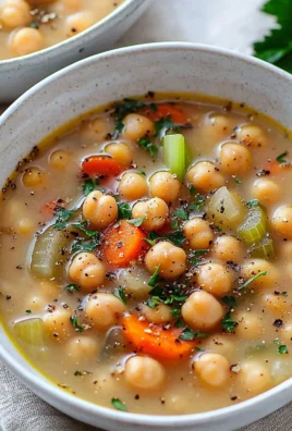 Bowl of hearty chickpea and white bean soup garnished with fresh herbs