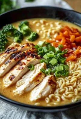 Bowl of creamy garlic chicken ramen with fresh herbs and toppings