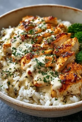 Creamy garlic chicken rice bowls topped with herbs and served in a white bowl.