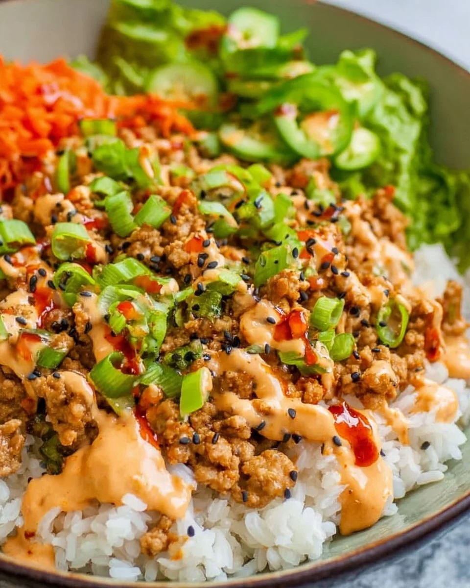 Ground Turkey Rice Bowl garnished with Bang Bang Sauce and fresh vegetables