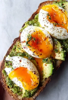 Pesto avocado toast topped with eggs on a plate