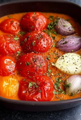 Bowl of roasted tomato and pepper soup garnished with fresh herbs.