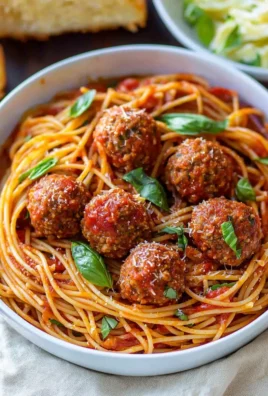 Plate of homemade spaghetti and meatballs with marinara sauce and herbs