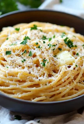 Plate of cheesy garlic parmesan spaghetti topped with parsley and grated cheese.