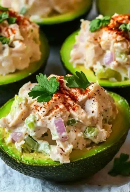 Delicious chicken salad stuffed avocado on a plate, garnished with herbs.