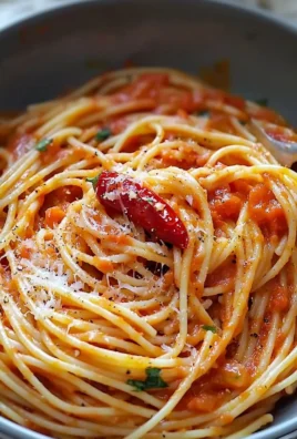 Plate of spaghetti with spicy tomato and pepper sauce garnished with herbs