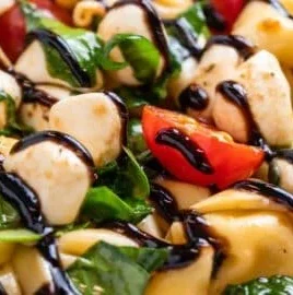 Delicious Caprese Salad with Tortellini topped with fresh basil and mozzarella