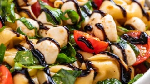 Delicious Caprese Salad with Tortellini topped with fresh basil and mozzarella