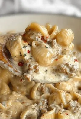 Bowl of creamy Italian sausage pasta garnished with herbs.
