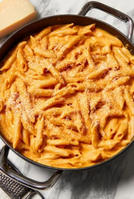 Creamy tomato pasta dish garnished with fresh basil, served in a bowl.