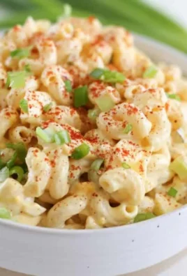 Deviled egg pasta salad in a bowl with fresh herbs and seasonings