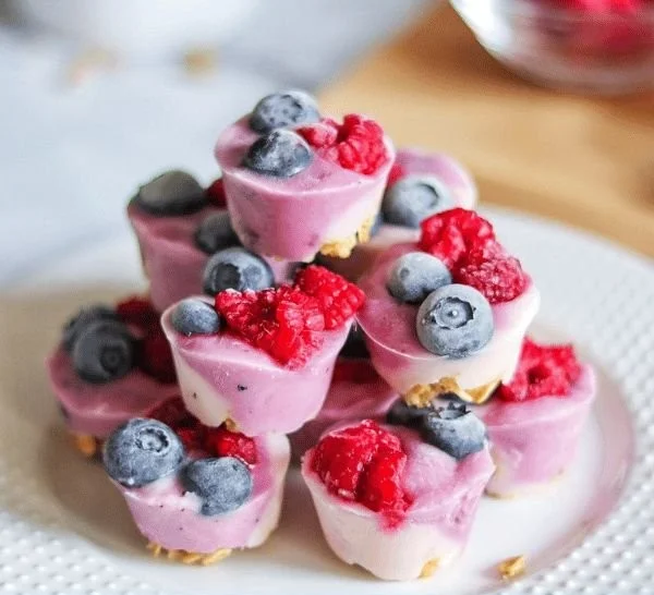 Frozen yogurt berry bites topped with fresh berries and a drizzle of honey.