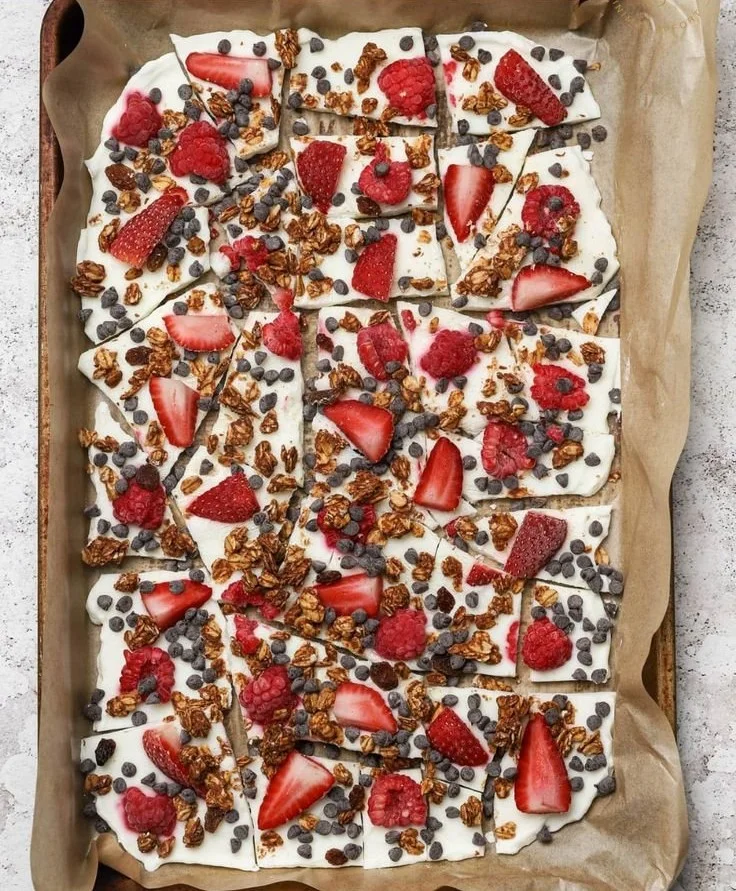 Greek Yogurt Bark topped with fruits and nuts on a marble surface