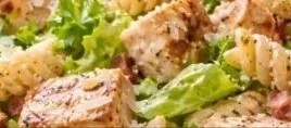 High-protein chicken caesar pasta salad topped with fresh ingredients and dressing
