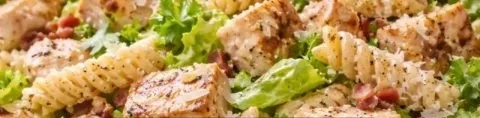 High-protein chicken caesar pasta salad topped with fresh ingredients and dressing