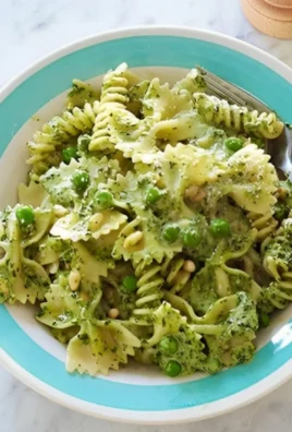 Ina Garten's pesto pasta salad with fresh ingredients and vibrant colors