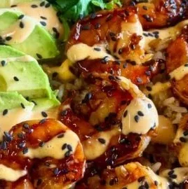 Delicious teriyaki shrimp rice bowl topped with vegetables and sesame seeds.
