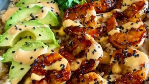 Delicious teriyaki shrimp rice bowl topped with vegetables and sesame seeds.