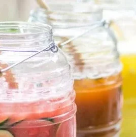 Four colorful agua fresca drinks served in glasses on a table