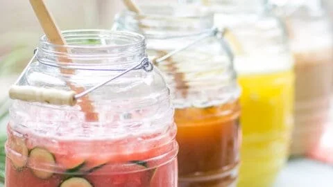 Four colorful agua fresca drinks served in glasses on a table