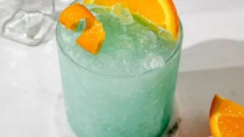 Bright Blue Hawaiian Mocktail served in a glass with pineapple and cherry garnishes.