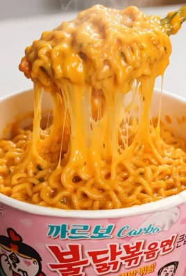 Bowl of carbonara spicy chicken ramen topped with herbs and chili.