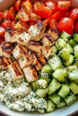 A delicious Greek Chicken Bowl topped with fresh vegetables and feta cheese.