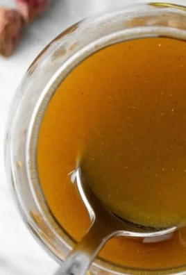 Homemade pistachio syrup in a glass jar with a spoon