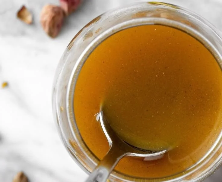 Homemade pistachio syrup in a glass jar with a spoon