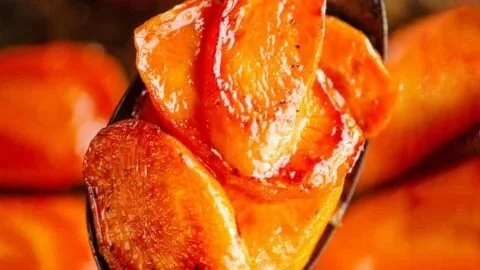 Hot honey glazed carrots on a plate garnished with herbs