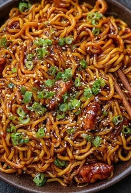 Bowl of Korean spicy chicken noodles topped with green onions and sesame seeds.