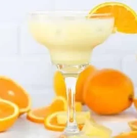 Orange, Pineapple & Coconut Mocktail served in a glass with fruits on the side.