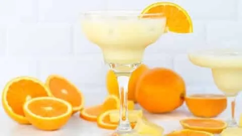 Orange, Pineapple & Coconut Mocktail served in a glass with fruits on the side.