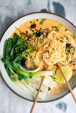 Bowl of quick spicy coconut noodles garnished with herbs and chili flakes