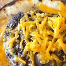 Smashed cheeseburger tacos with toppings on a white plate.