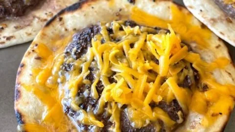 Smashed cheeseburger tacos with toppings on a white plate.