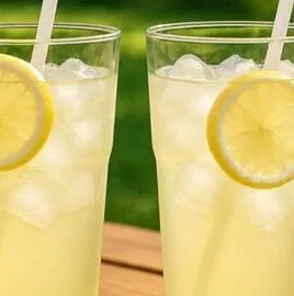 A refreshing glass of homemade lemonade with lemon slices on the rim.