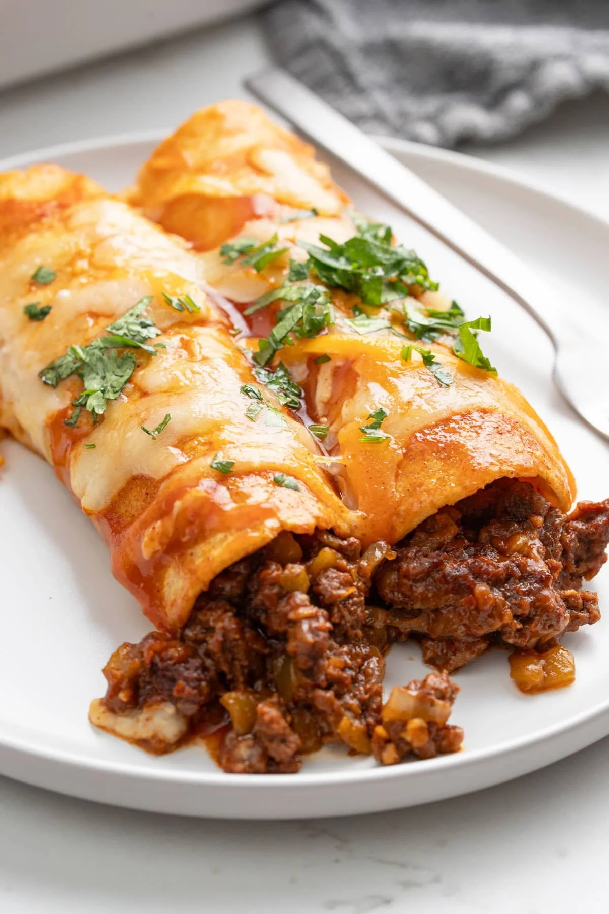 Delicious beef enchiladas topped with cheese and enchilada sauce