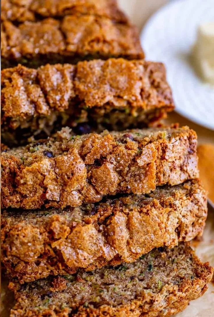 Freshly baked zucchini bread loaf with slices on a wooden table