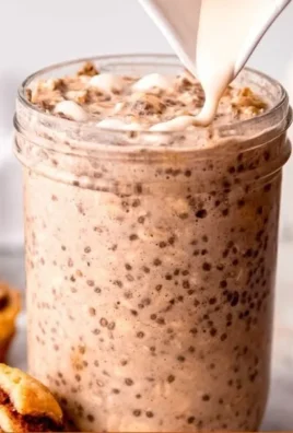 Bowl of cinnamon roll overnight oats topped with nuts and cinnamon
