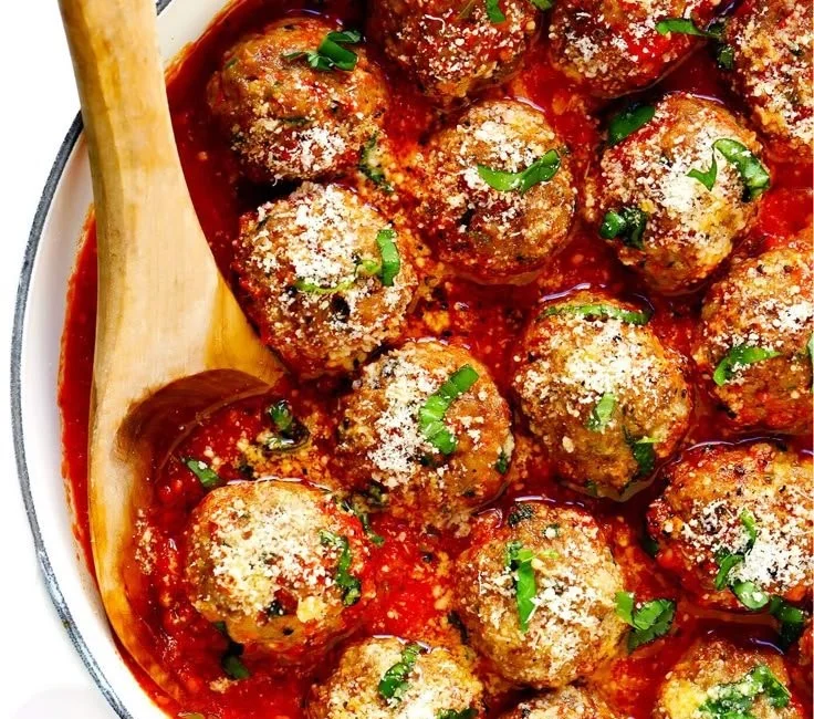 Plate of classic baked meatballs with marinara sauce and herbs