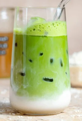 Creamy Coconut Matcha Latte in a glass with green matcha powder and coconut milk.