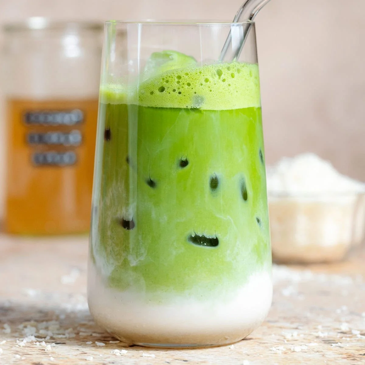 Creamy Coconut Matcha Latte in a glass with green matcha powder and coconut milk.