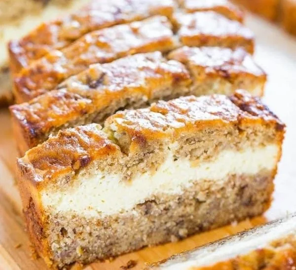 Slice of cream cheese-filled banana bread on a wooden cutting board