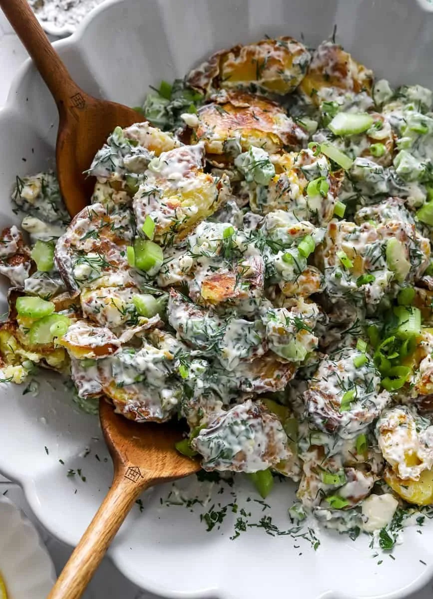 Delicious crispy smashed potato salad served in a bowl with fresh herbs.