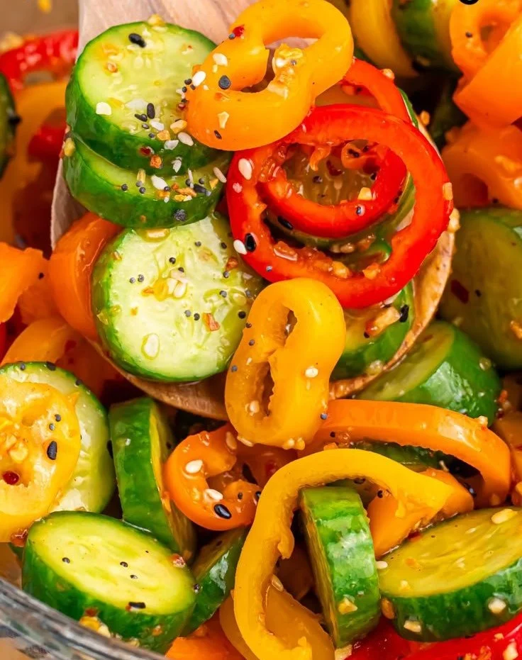 Cucumber and sweet pepper salad served in a bowl with fresh herbs.