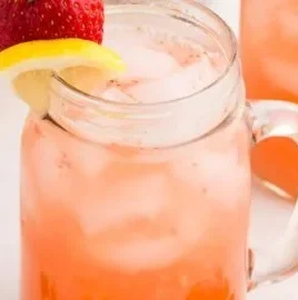 A glass of refreshing strawberry lemonade with fresh strawberries and lemon slices.