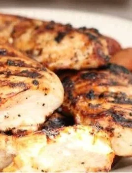 Juicy grilled chicken breasts garnished with herbs on a plate