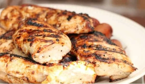 Juicy grilled chicken breasts garnished with herbs on a plate